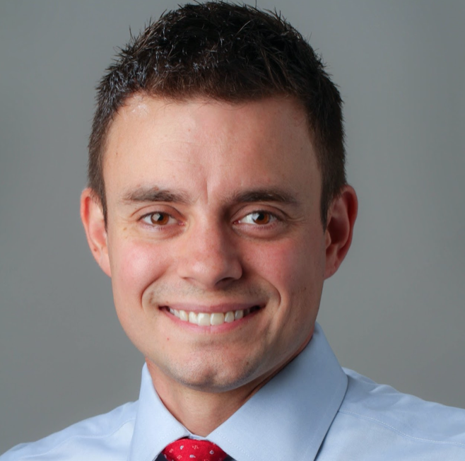 Scott J. Peters, a young white man with dark hair wearing a blue collared shirt and red tie.